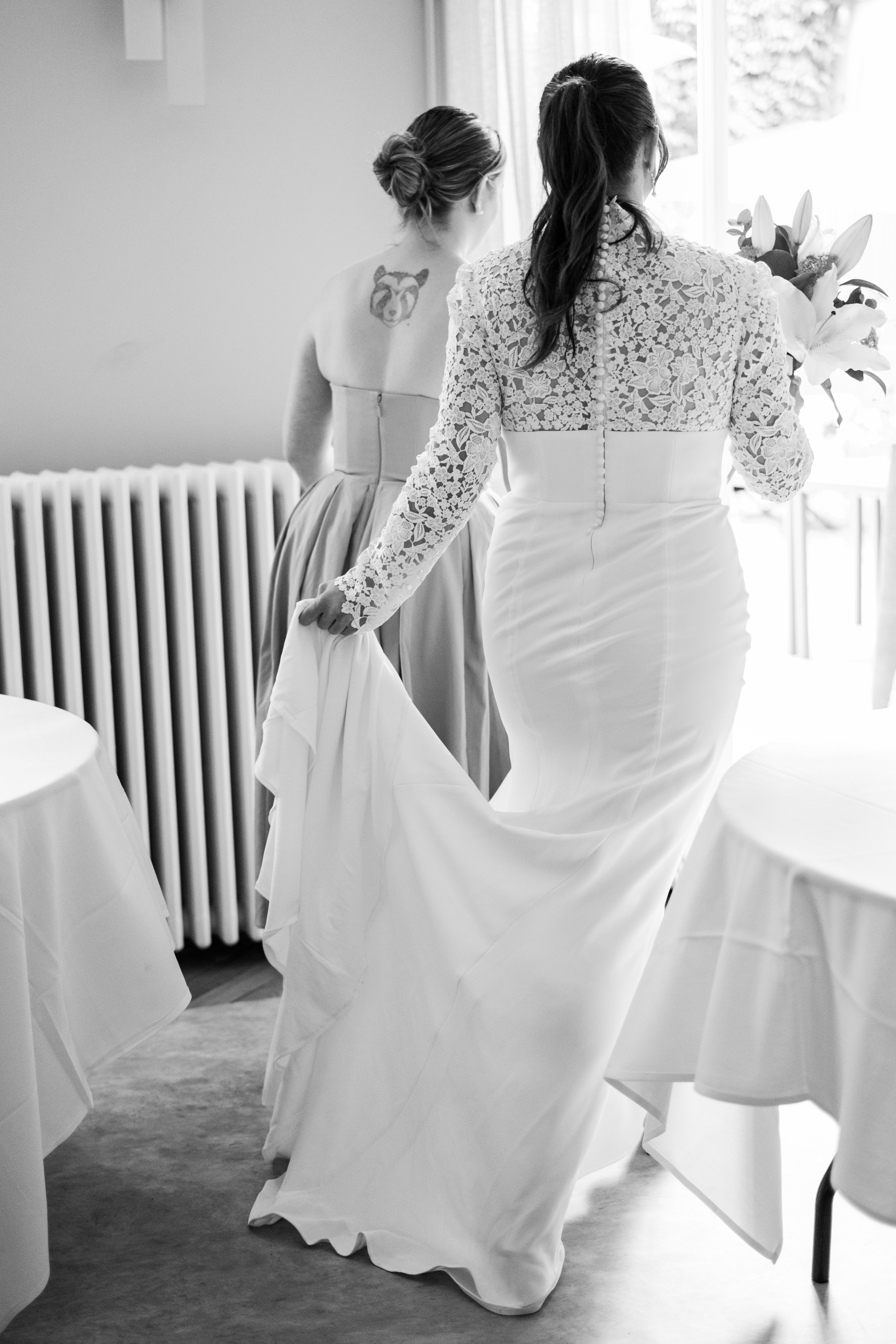 photo de dos d'une mariée avec son bouquet, tenant sa robe en vue de la cérémonie
